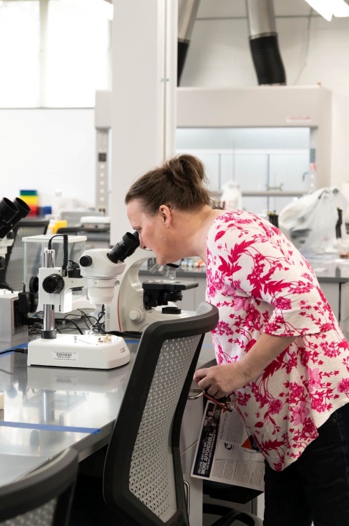 woman looking into a microscope in a lab environment