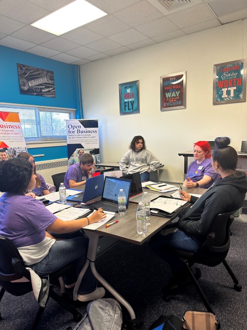 students sitting around a square table discussing a topic